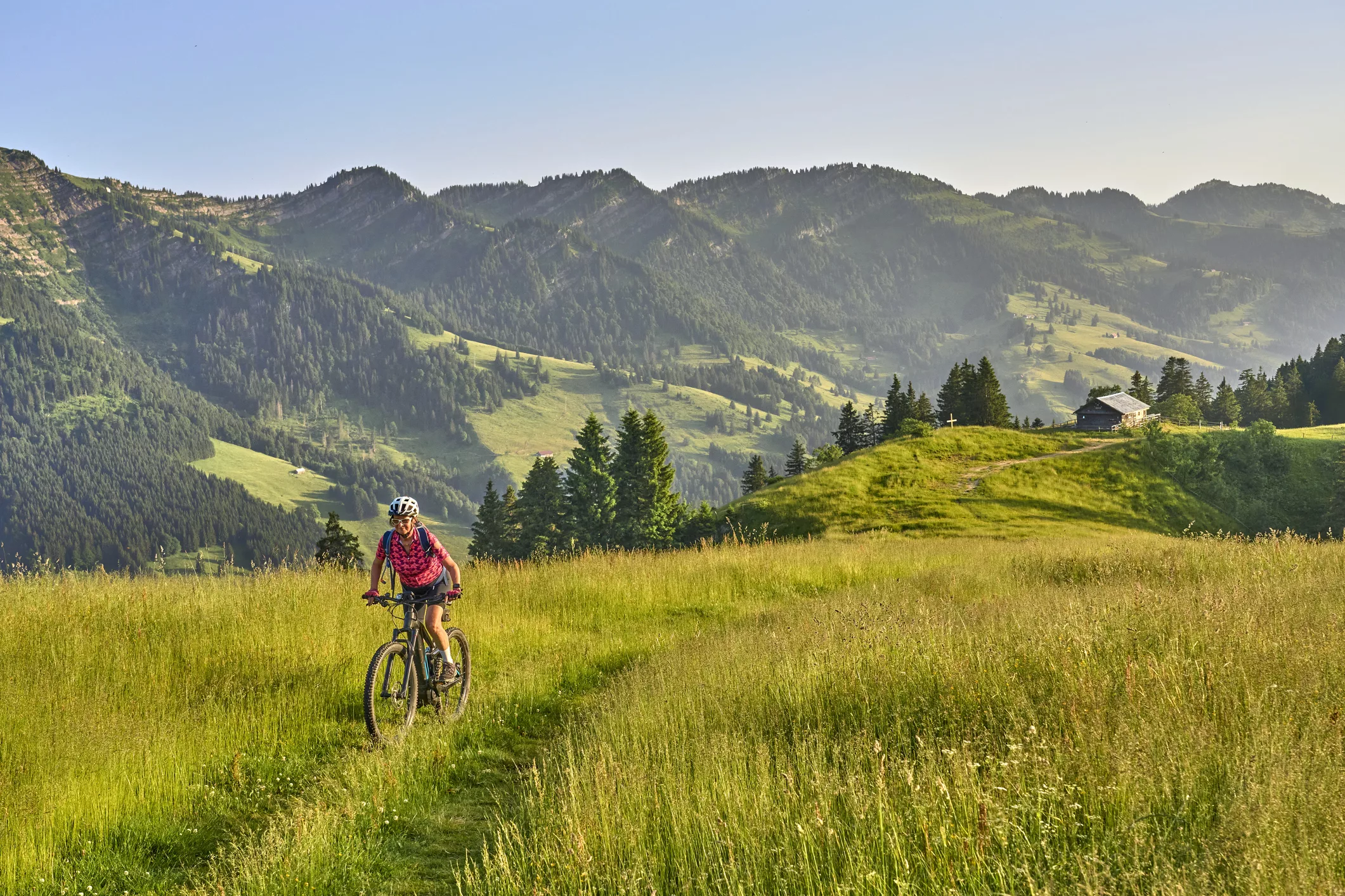 Woman bicycling along a valley in the French commune of La Giettaz