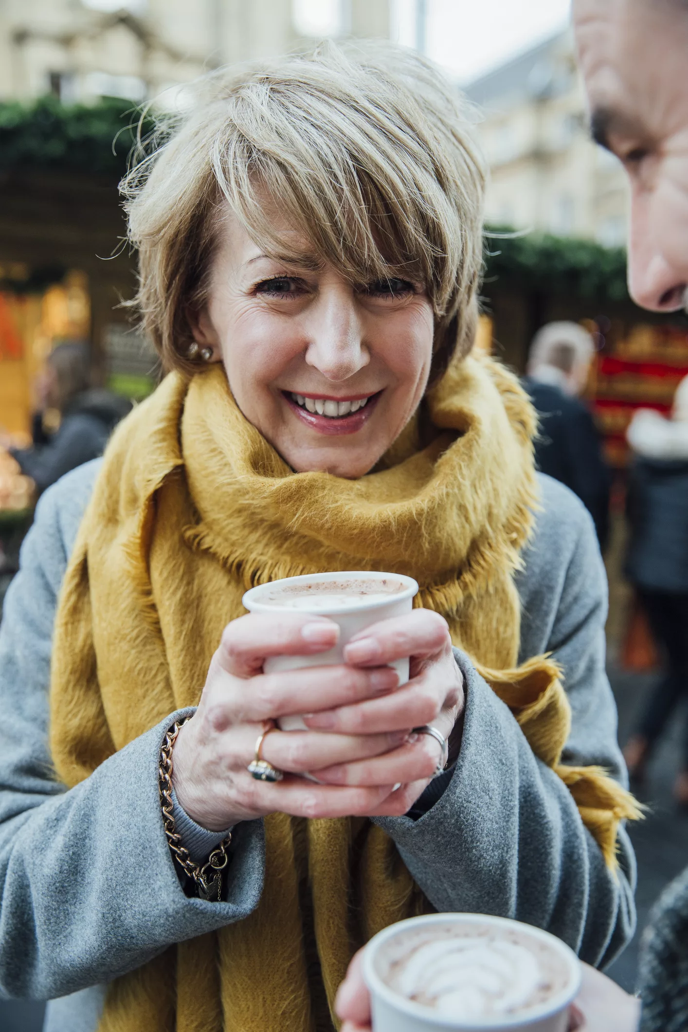 A cheerful woman drinking hot chocolate during her trip aboard an Elbe River Cruise.