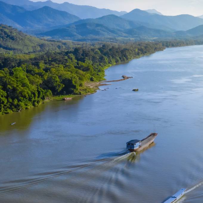 Aerial view of a ship sailing across the lush Mekong River.