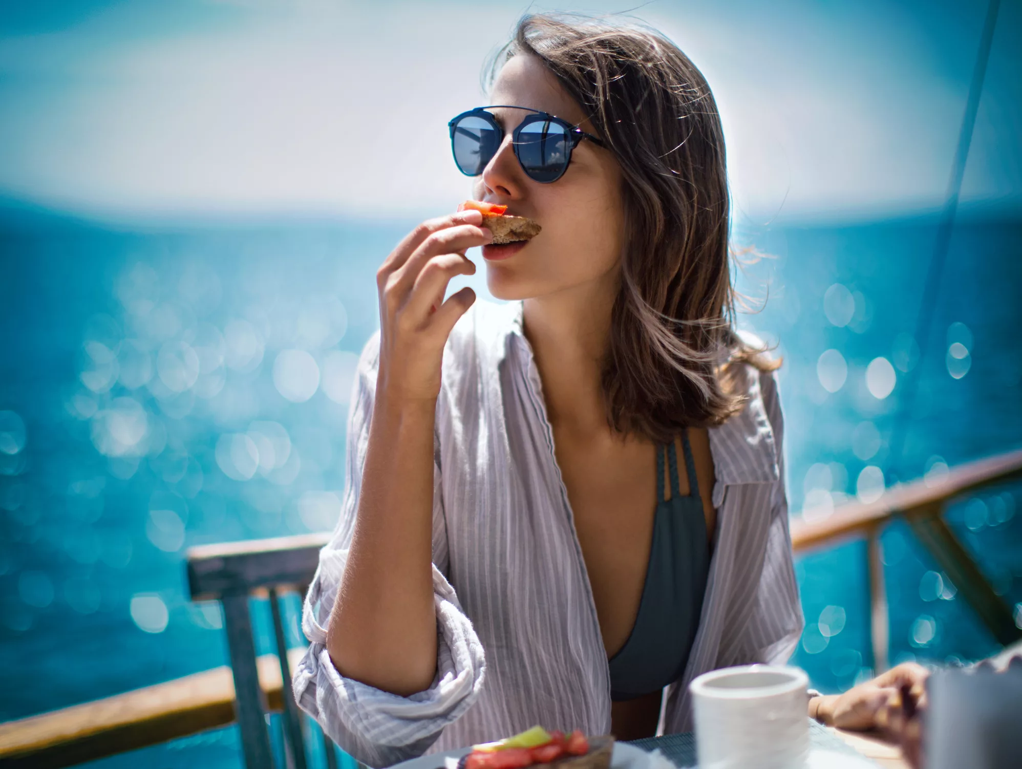 A female cruiser wearing sunglasses, enjoying delicious finger food on the deck of a Duoro River cruise ship